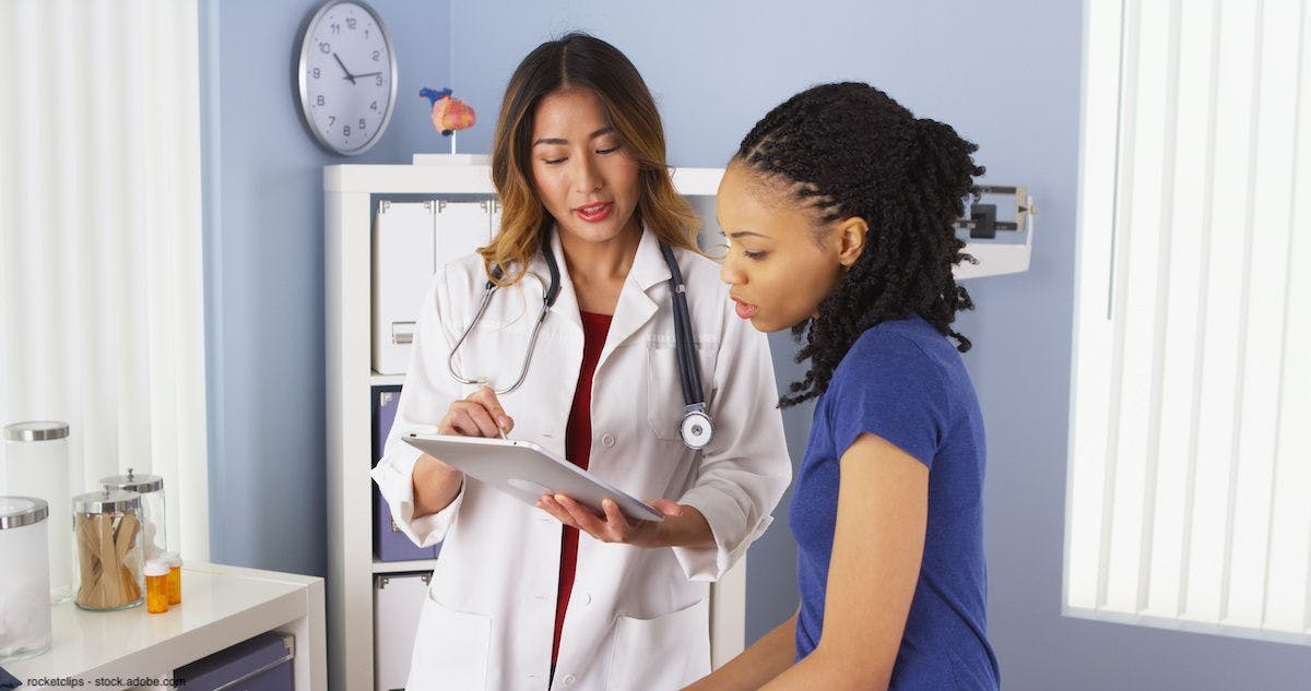 Asian female doctor using a tablet to explain information to an African-American female patient