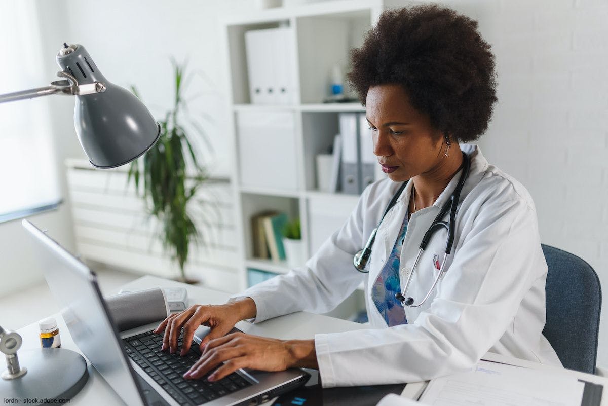 Female African-American doctor typing on a laptop computer