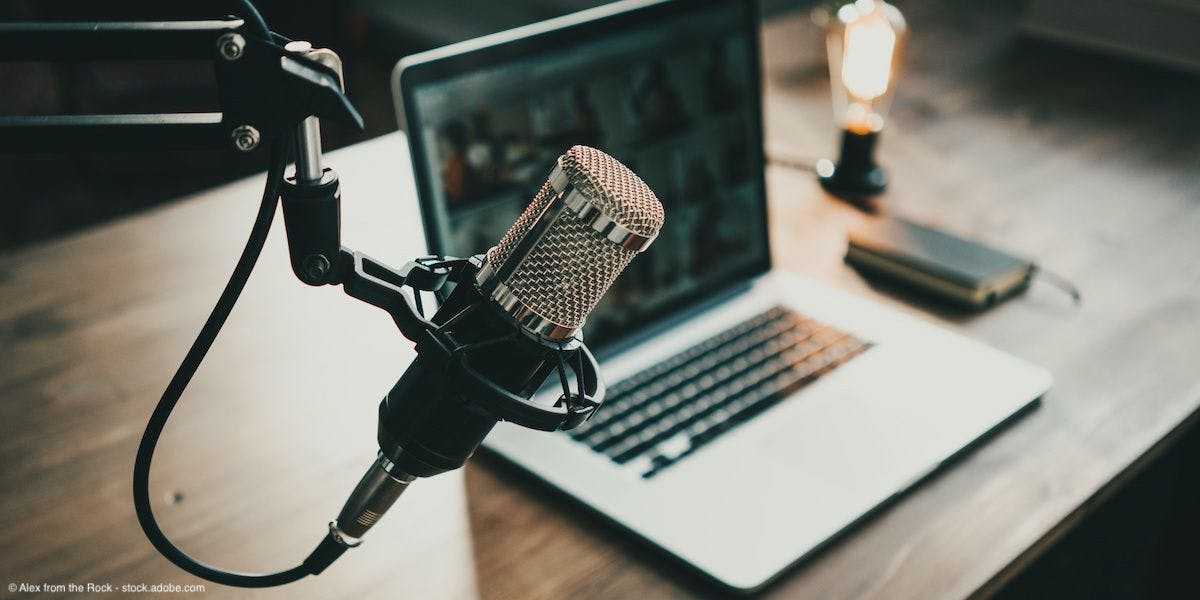 Laptop and podcast microphone sitting on table